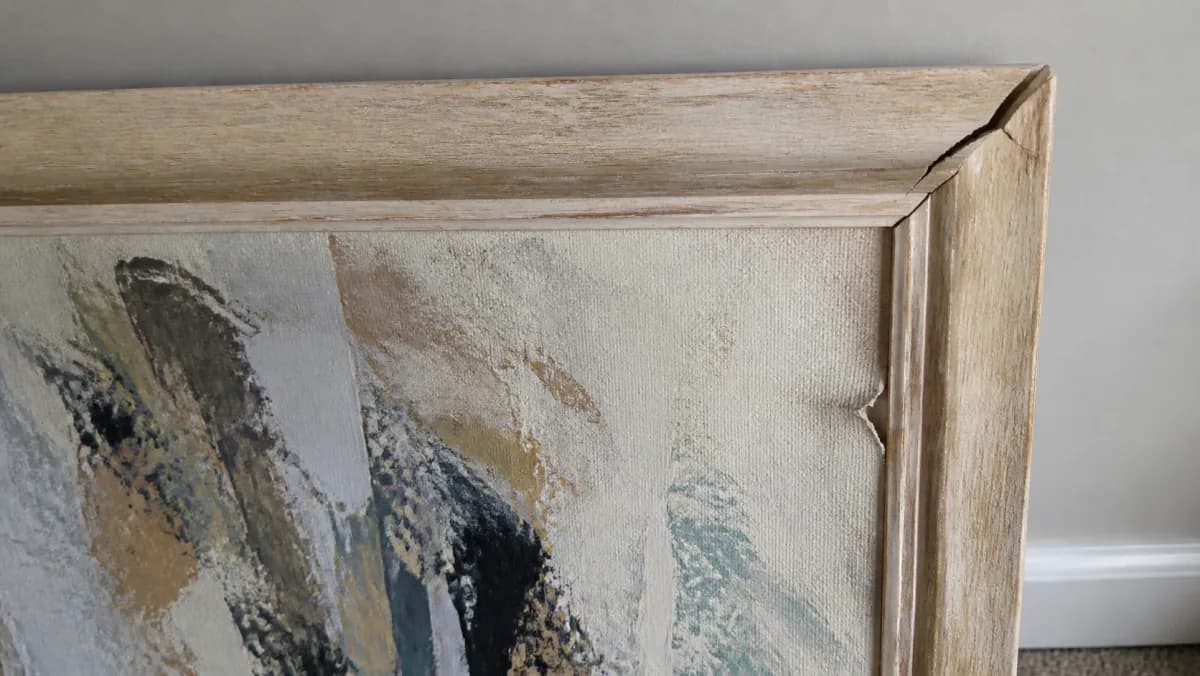 A cracked picture frame and a small tear near the edge of an abstract canvas